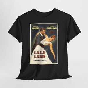Może przedstawiać: Czarny t-shirt z krótkim rękawem z nadrukiem graficznym plakatu filmowego La La Land. Wzór przedstawia mężczyznę w garniturze pochylającego kobietę w białej sukience, z napisem Emma Stone, Ryan Gosling, La La Land oraz Damien Chazelle.