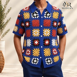 Könnte beinhalten: Ein kurzärmeliges Hemd mit Knopfleiste und einem blauen Häkelmuster aus Granny Squares mit roten, gelben, weißen und schwarzen Akzenten. Das Hemd hat einen klassischen Kragen und eine Knopfleiste. Der Schriftzug Modern Style Room ist zu sehen.