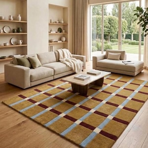 May include: A rectangular area rug featuring a grid pattern of mustard yellow squares separated by intersecting stripes in deep burgundy and light blue, with small white squares at each intersection point, laid on a light wood floor.