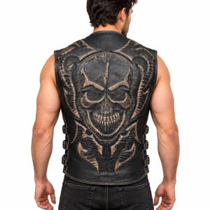 May include: A black leather vest featuring a large, embossed skull design on the back with distressed brown highlights. The sleeveless garment includes side straps with metal buckles for an adjustable fit, showcasing a detailed, textured finish.