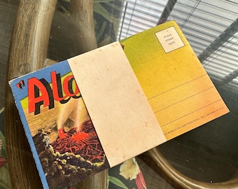 May include: Vintage postcard with the word "Aloha" on the front, featuring a colorful image of lava. The back of the postcard is yellow with lines for writing and a space for a stamp. A blank card is tucked inside.
