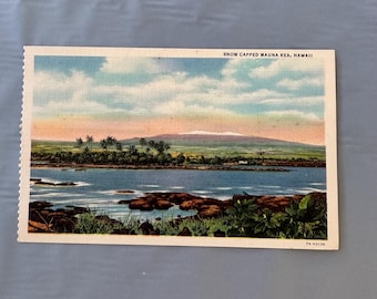 May include: Vintage postcard featuring a scenic view of Snow Capped Mauna Kea, Hawaii. The image shows a blue body of water, a green landscape with palm trees, and a mountain range under a cloudy sky. The postcard has a white border and the text "SNOW CAPPED MAUNA KEA, HAWAII".