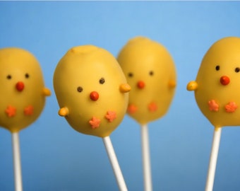 May include: Four yellow cake pops decorated to look like chicks. Each cake pop has a red beak, black eyes, and orange sprinkles.