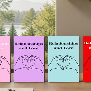 May include: Four rectangular books with solid covers in pink, purple, light blue, and red. Each book features the black text "Relationships and Love" above a black line-art illustration of two hands forming a heart shape centered on the cover.