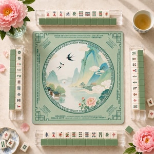 May include: A Mahjong set featuring a square green play mat with a central illustration of mountains, swallows, and flowers, surrounded by four clear tile racks holding white tiles with red, green, and black symbols and characters.