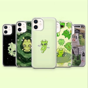 May include: Five clear phone cases featuring green alien cat graphics. Designs include a black background with a glowing cat, a swirling green galaxy pattern, a central alien cat, a pattern of small green cats, and a newspaper collage with a cat.