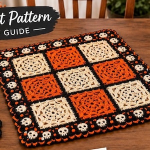 Peut inclure: Un tapis carré au crochet et quatre dessous de verre assortis avec un motif de toile d'araignée orange et crème, bordés d'un contour noir avec des crânes blancs. Le texte "Crochet Pattern PDF GUIDE" apparaît en haut à gauche.