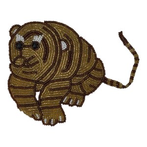 Op de afbeelding: Een tijgervormige patch gemaakt van kleine glaskralen in goud-, bruin- en wittinten. Het ontwerp heeft een streeppatroon, zwarte kraaloogjes en een lange, slanke staart die naar rechts uitsteekt, alles in een dichte, getextureerde formatie.