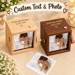 Puede incluir: Dos cajas de música cuadradas de madera, una de roble claro y otra de nogal oscuro, con una manivela lateral. Cada caja está grabada con el texto I love you always 22.07.2025 y un corazón. Una foto de una pareja se muestra en la parte frontal.