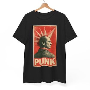Puede incluir: Una camiseta negra de manga corta con un estampado gráfico rectangular de una persona de perfil con un peinado mohicano de puntas. El estampado tiene un fondo rojo, una chaqueta oscura y la palabra PUNK en letras blancas grandes abajo.