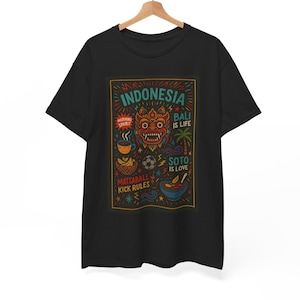 May include: A black short-sleeve t-shirt featuring a colorful graphic print with the text INDONESIA, MORNING SPIRIT, BALI IS LIFE, SOTO IS LOVE, MATSABALL, and KICK RULES. The design includes a central mask, a coffee cup, a bowl of food, and a palm tree.