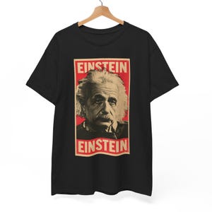 Op de afbeelding: Een zwart T-shirt met korte mouwen en een rechthoekige grafische print op de borst. De print toont een portret van Albert Einstein in sepiatinten tegen een rode achtergrond, met het woord EINSTEIN in het wit erboven en eronder.