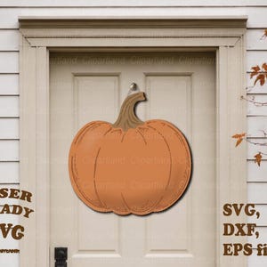 May include: A pumpkin-shaped wall hanging featuring a smooth orange surface with etched lines and a brown stem. The text LASER READY SVG, SVG, DXF, EPS files is displayed in brown lettering on the sides of the pumpkin wall decor.