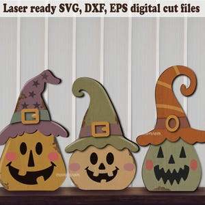 Pode incluir: Três figuras em forma de abóbora com chapéus de bruxa, com o texto Laser ready SVG, DXF, EPS digital cut files. As abóboras têm traços pretos, bochechas rosadas e chapéus roxos, verdes e laranja, cada um com uma fivela.