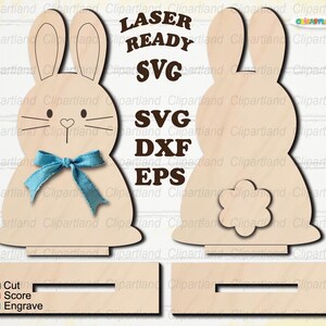 May include: Wooden laser-ready bunny cutouts with a blue bow, whiskers, and heart nose. The design includes front and back views, along with a base. Text includes "LASER READY SVG SVG DXF EPS" and color-coded cutting instructions.