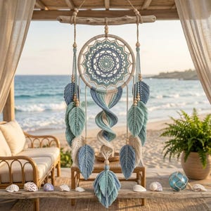 May include: A macrame wall hanging featuring a central circular web in shades of blue and cream, suspended from a piece of driftwood. The design includes multiple hanging leaf-shaped macrame elements and a central spiral, accented with wooden beads.