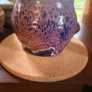 May include: A rounded ceramic pot featuring a glossy glaze with a mottled pattern of deep purple, magenta, and dark blue hues. The surface displays a textured, drip-like effect with small circular spots and darker streaks throughout the exterior.