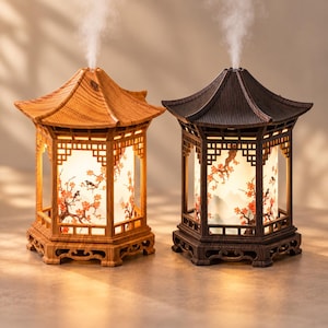 May include: Two pagoda-shaped humidifiers, one in light wood and one in dark wood, each featuring a hexagonal frame with intricate lattice details and a central cylindrical panel decorated with orange cherry blossoms and black birds, emitting mist.