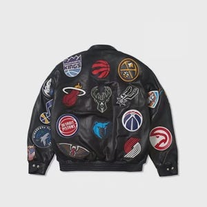 May include: A black leather varsity jacket featuring numerous colorful embroidered patches of various professional basketball team logos, including the Sacramento Kings, Detroit Pistons, and others, with a ribbed collar, cuffs, and hem.