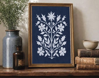 May include: A framed rectangular wall art piece featuring a symmetrical white botanical illustration of flowers, leaves, and berries centered on a deep navy blue background. The artwork is enclosed in a thin, metallic gold-toned frame.