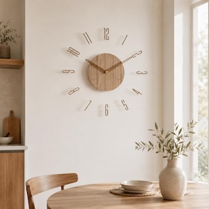 Peut inclure: Une horloge murale composée d'un cadran central en bois clair circulaire avec des aiguilles fines dorées. Les chiffres de un à douze sont des pièces métalliques dorées individuelles fixées au mur en cercle autour du centre.
