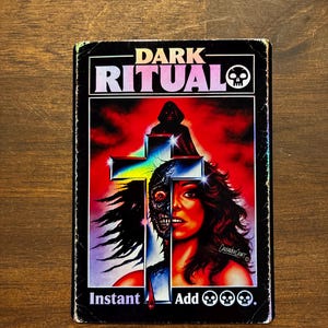 May include: A rectangular trading card titled DARK RITUAL with a skull icon. The artwork features a hooded figure, a cross, and a face split between human and skeletal features against a red background. The text reads Instant Add followed by three skull symbols.