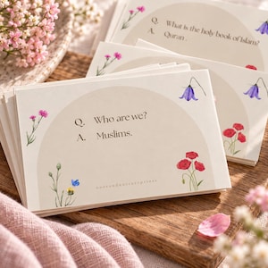 Peut inclure: Une pile de cartes rectangulaires blanches avec un motif en demi-cercle beige, des illustrations florales et du texte noir. La carte du dessus indique Q. Who are we? A. Muslims. Les cartes présentent des fleurs roses, rouges et bleues.