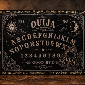 May include: A rectangular black Ouija board tray featuring gold leaf accents and metallic gold handles. The surface displays the alphabet, numbers 1 through 9, the words YES, NO, OUIJA, MYSTIFYING ORACLE, and GOOD BYE, with sun, moon, and star illustrations.