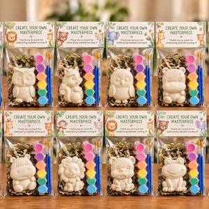 May include: Twelve clear plastic party favor bags, each containing a white animal-shaped plaster figurine, a strip of six small paint pots, and a paintbrush. The header card reads: CREATE YOUR OWN MASTERPIECE. Thank you so much for celebrating Isabelle turning 4!