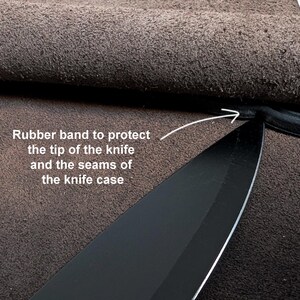 K&ouml;nnte beinhalten: Eine schwarze Messerklinge in einer braunen Lederscheide mit einem Gummiband an der Spitze zum Schutz. Der Text lautet: Rubber band to protect the tip of the knife and the seams of the knife case, mit einem Pfeil auf das Gummiband.