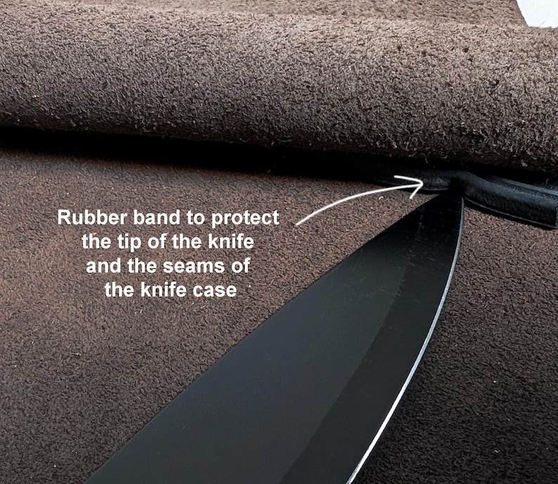 K&ouml;nnte beinhalten: Eine schwarze Messerklinge in einer braunen Lederscheide mit einem Gummiband an der Spitze zum Schutz. Der Text lautet: Rubber band to protect the tip of the knife and the seams of the knife case, mit einem Pfeil auf das Gummiband.