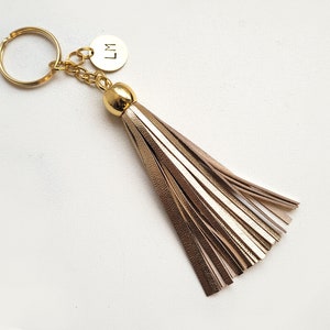 May include: Gold keychain with a gold tassel and a round charm with the initials "LM" engraved on it.