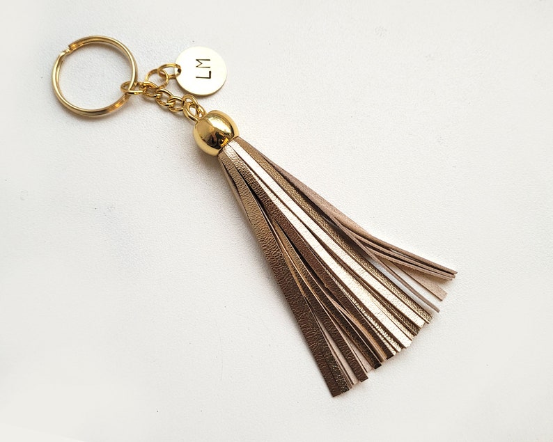 May include: Gold keychain with a gold tassel and a round charm with the initials "LM" engraved on it.