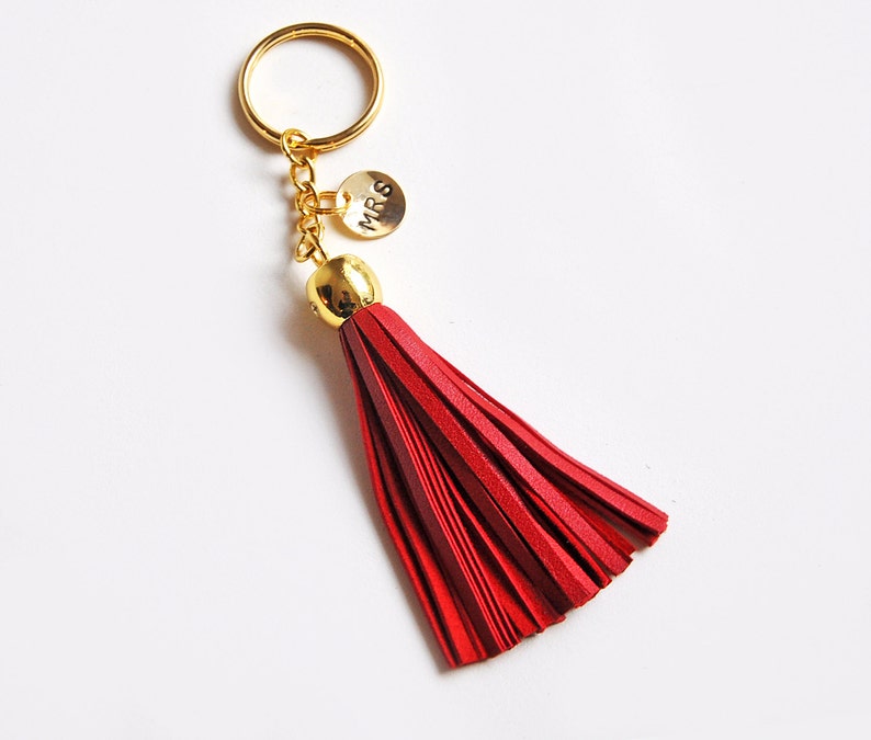 May include: A red leather tassel keychain with a gold key ring and a small gold charm that says "Mrs."