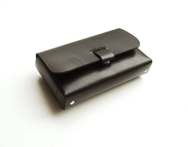 May include: A black leather clutch with a flap closure and a silver buckle. The clutch has a smooth, textured surface and is accented with silver rivets.