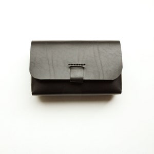 May include: A black leather wallet with a flap closure and a stitched detail.