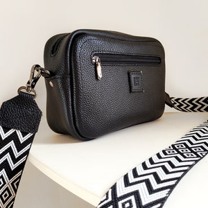 Black leather crossbody bag with a wide geometric pattern fabric strap