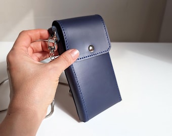May include: A navy blue leather crossbody bag with a flap closure and silver-tone hardware. The bag has a rectangular shape and a silver chain strap. The stitching is a lighter blue color. The bag is approximately 7 inches tall.