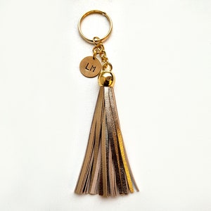 May include: Gold keychain with a leather tassel and a round charm with the initials "LM" engraved on it.