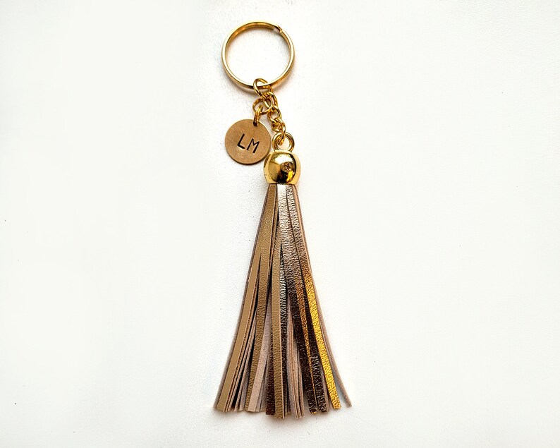 May include: Gold keychain with a leather tassel and a round charm with the initials "LM" engraved on it.