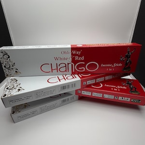 Puede incluir: Tres cajas rectangulares de varitas de incienso Ohli-Way White & Red Chango. El empaque es blanco y rojo con detalles florales negros, con el texto "Chango Incense Sticks 7 in 1" y una ilustración de una figura sosteniendo un bastón.