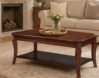 May include: A rectangular wooden coffee table with a rich dark brown finish, featuring a smooth top surface with a subtle chevron pattern, curved legs with carved floral details at the top, and a lower shelf for storage, topped with a woven tray.