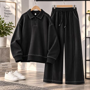 Può includere: Un completo nero composto da una polo a maniche lunghe con colletto, tre bottoni e cuciture bianche a contrasto, abbinato a pantaloni larghi coordinati con elastico in vita con coulisse e cuciture bianche a contrasto.
