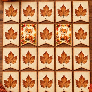 May include: A set of twenty rectangular pennants arranged in a grid, featuring nineteen pennants with a single brown maple leaf and two pennants with a cartoon fox illustration surrounded by autumn leaves and acorns on a cream background.