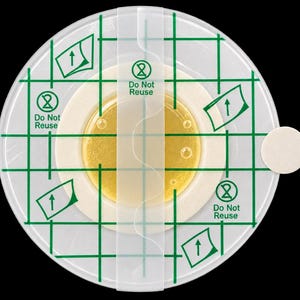 May include: A circular, transparent adhesive patch with a central yellow gel reservoir. The surface features a green grid pattern, directional arrows, and the text "Do Not Reuse" printed in green. A vertical translucent strip covers the center.