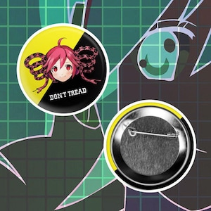 May include: A circular pin-back button featuring a split yellow and black background. The design includes a stylized anime character with pink hair and red eyes, flanked by a coiled snake. The text DON'T TREAD is printed in white at the bottom.