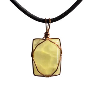 May include: A rectangular, pale yellow gemstone pendant wrapped in copper wire, suspended from a black cord. The pendant has rounded corners and a slightly translucent appearance. The wire is intricately woven around the stone, creating a decorative frame.