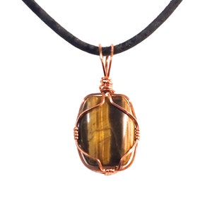 May include: A pendant featuring a polished, rectangular tiger's eye stone wrapped in copper wire. The stone has brown and gold bands. The pendant hangs from a black cord.