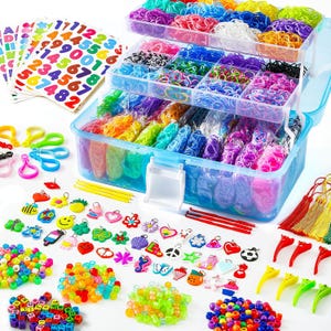 Può includere: Una custodia in plastica trasparente a più livelli riempita con elastici colorati, accompagnata da vari articoli per il fai da te tra cui adesivi con lettere e numeri, ciondoli in plastica, perline colorate, piccoli ganci e nappe decorative.