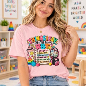 May include: A light pink t-shirt featuring a colorful graphic with the text THINGS I SAY all day as an RBT, a checklist with phrases like Let's go, First... then, Use your words, Great job, Let's clean up, and You can do it, plus icons.